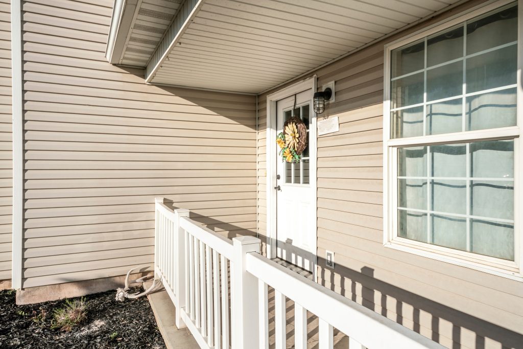 Front door exterior of a house with vinyl wall sidings